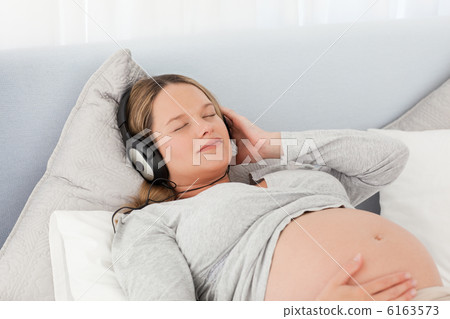 Pretty future mom listening to the music lying on a bed Pretty future mom listening to the music lying on a bed 6163573