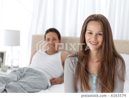 Pretty girl sitting on the edge of her bed with her boyfriend Pretty girl sitting on the edge of her bed with her boyfriend 6163574