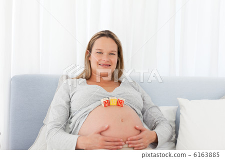 Portrait of a pregnant woman having mom letters on her belly 6163885