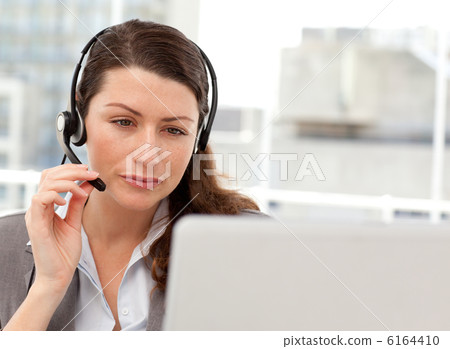Concentrated businesswoman working on her laptop while calling 6164410