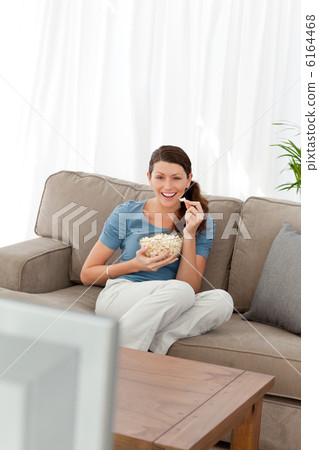 Woman laughing while watching a movie on television in the livin 6164468