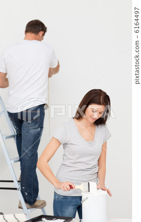 Happy couple painting together a room Happy couple painting together a room 6164497
