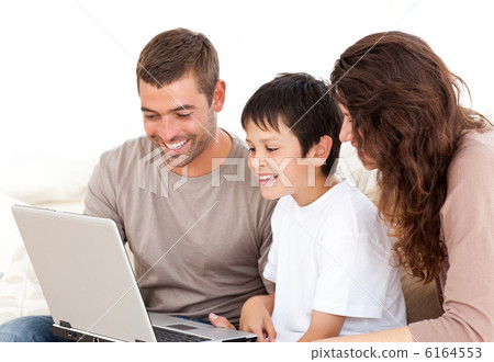 Cute family working on their laptop together sitting on the sofa Cute family working on their laptop together sitting on the sofa 6164553