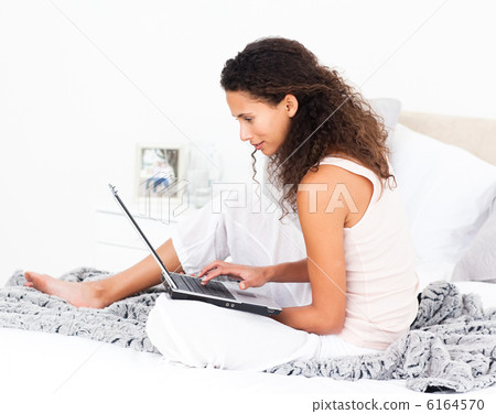 Pretty woman working on her laptop on her bed Pretty woman working on her laptop on her bed 6164570