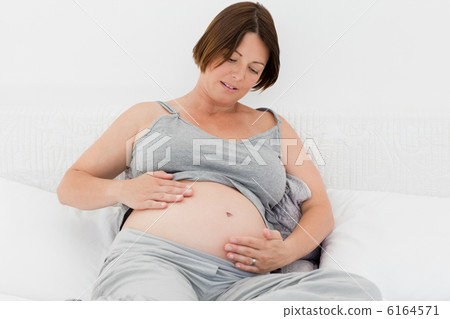 Pregnant woman cuddling her belly 6164571