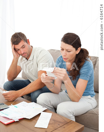 Stressed couple doing their accounts sitting on the sofa Stressed couple doing their accounts sitting on the sofa 6164714