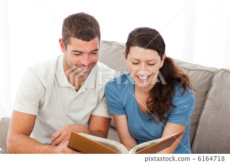 Lovely couple reading a book together on the sofa Lovely couple reading a book together on the sofa 6164718