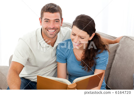 Pretty woman reading a book with her boyfriend on the sofa Pretty woman reading a book with her boyfriend on the sofa 6164720