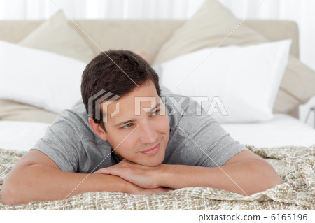 Happy man lying on the edge of his bed Happy man lying on the edge of his bed 6165196