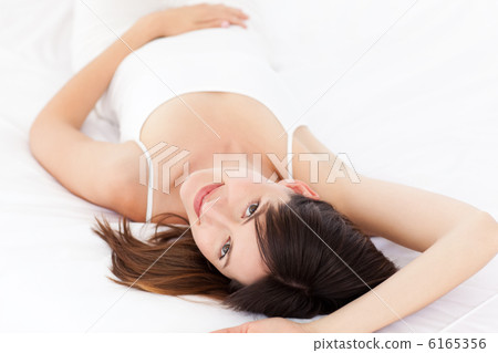 Pretty woman lying down on her bed 6165356