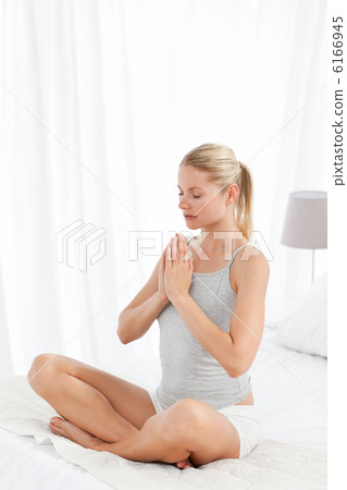 Beautiful woman practicing yoga on her bed 6166945