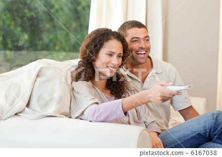 Couple watching tv in their living room at home Couple watching tv in their living room at home 6167038