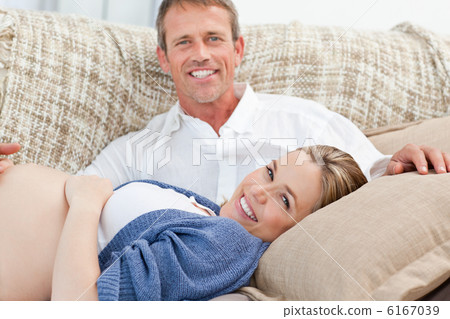 Happy pregnant woman with her husband on their sofa Happy pregnant woman with her husband on their sofa 6167039