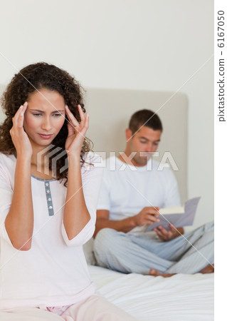 Woman having a headache while her husband is reading 6167050