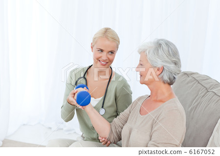 Beautiful nurse helping her patient to do exercises Beautiful nurse helping her patient to do exercises 6167052