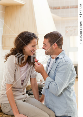 Lovers eating a strawberry in their kitchen Lovers eating a strawberry in their kitchen 6167286