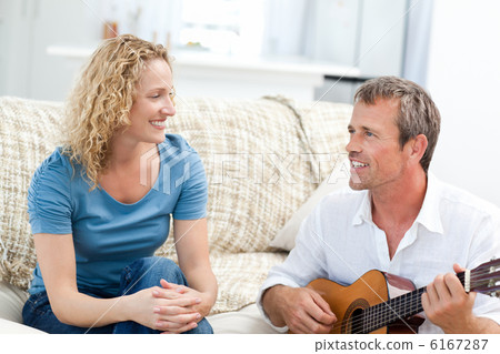 Romantic man playing guitar for her wife at home Romantic man playing guitar for her wife at home 6167287