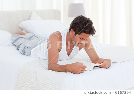 Man reading a book on his bed Man reading a book on his bed 6167294