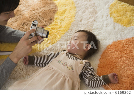 A father taking a baby's sleeping face with a digital camera 6169262