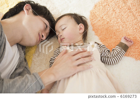 A father laying a baby on bed 6169273