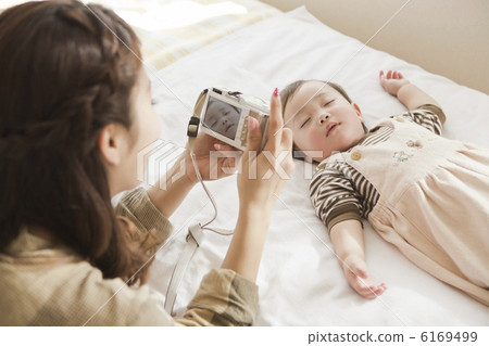 Mother taking a baby's sleeping face with a digital camera Mother taking a baby's sleeping face with a digital camera 6169499