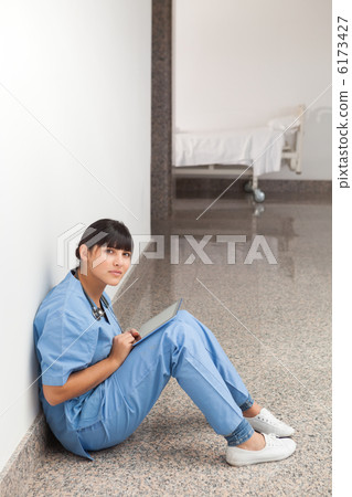 Nurse sitting on the ground with tablet computer Nurse sitting on the ground with tablet computer 6173427