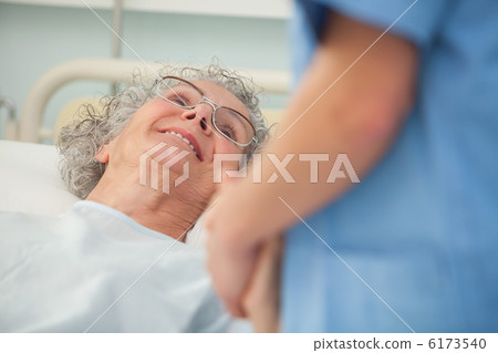 Elderly patient looking up at nurse Elderly patient looking up at nurse 6173540