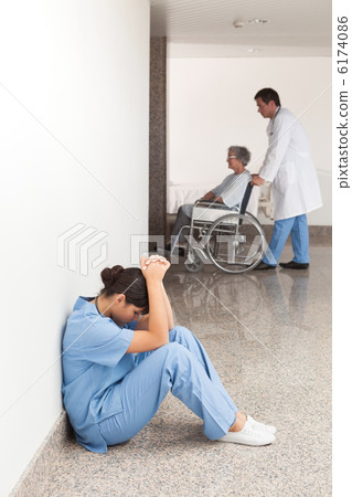 Nurse sitting in the hallway getting depressed 6174086