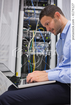 Man using laptop beside servers Man using laptop beside servers 6174127