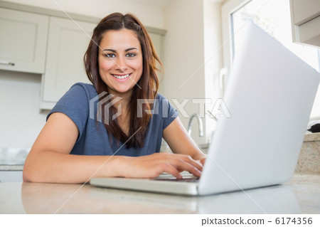 Woman smiling and using laptop 6174356