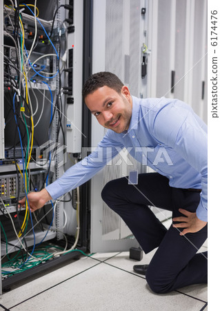 Smiling man adjusting cable in the server Smiling man adjusting cable in the server 6174476