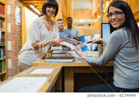 Librarian scanning book and handing to woman Librarian scanning book and handing to woman 6174494