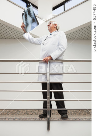 Doctor looking at x-ray leaning against railing 6174496