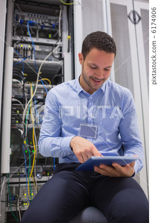 Technician using tablet pc to work on servers Technician using tablet pc to work on servers 6174906