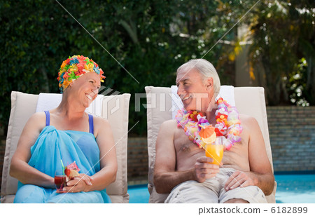 Mature couple drinking a cocktail beside the swimming pool Mature couple drinking a cocktail beside the swimming pool 6182899