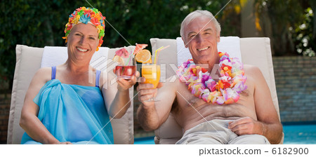Mature couple drinking a cocktail  beside the swimming pool 6182900