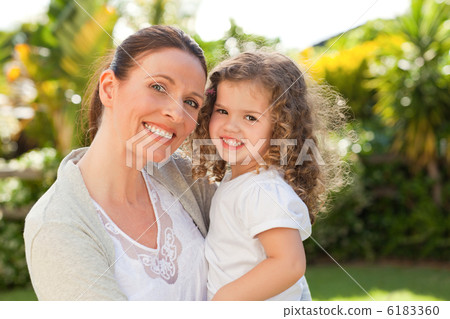 Mother with her daughter looking at the camera in the garden Mother with her daughter looking at the camera in the garden 6183360