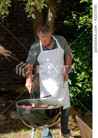 Handsome man having a barbecue in the garden Handsome man having a barbecue in the garden 6183595
