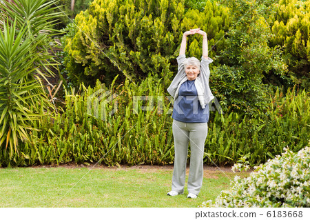 Retired woman doing her streches in the garden Retired woman doing her streches in the garden 6183668