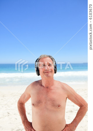 Retired man listening to some music on the beach Retired man listening to some music on the beach 6183670