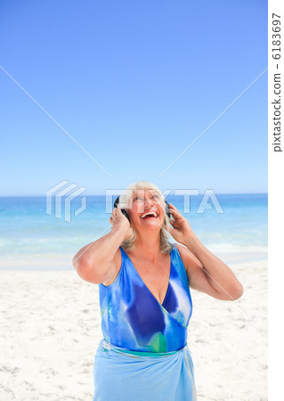 Senior woman listening to some music beside the sea 6183697
