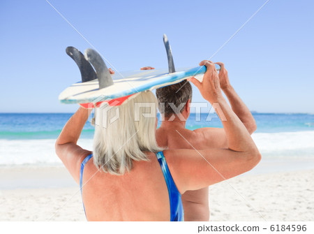 Senior couple with their surfboard 6184596