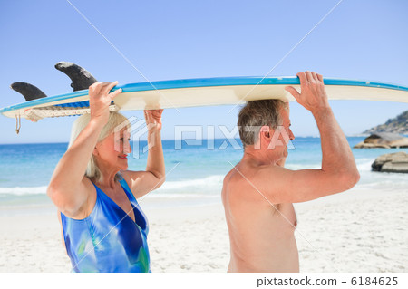 Senior couple with their surfboard 6184625