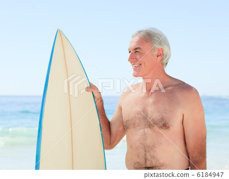 Retired  man with his surfboard 6184947