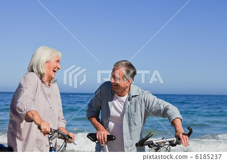 Retired couple with their bikes on the beach 6185237