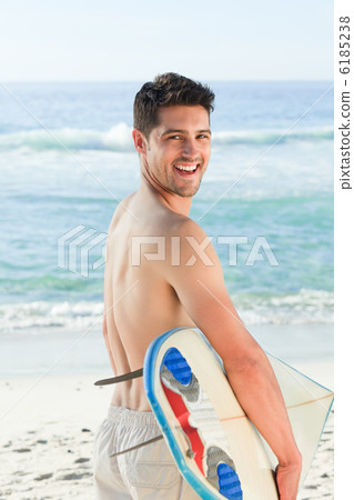 Handsome man beside the sea with his surfboard 6185238