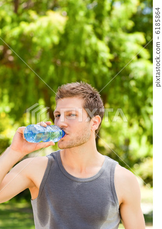 Sporty man drinking water in the park Sporty man drinking water in the park 6185864