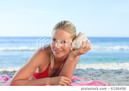 Woman listening to a shell Woman listening to a shell 6186406