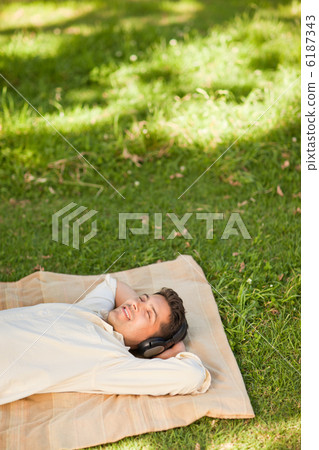 Young man listening to music in the park Young man listening to music in the park 6187343