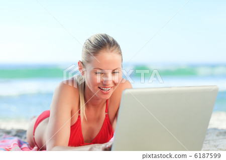 Lovely woman working on her laptop at the beach Lovely woman working on her laptop at the beach 6187599
